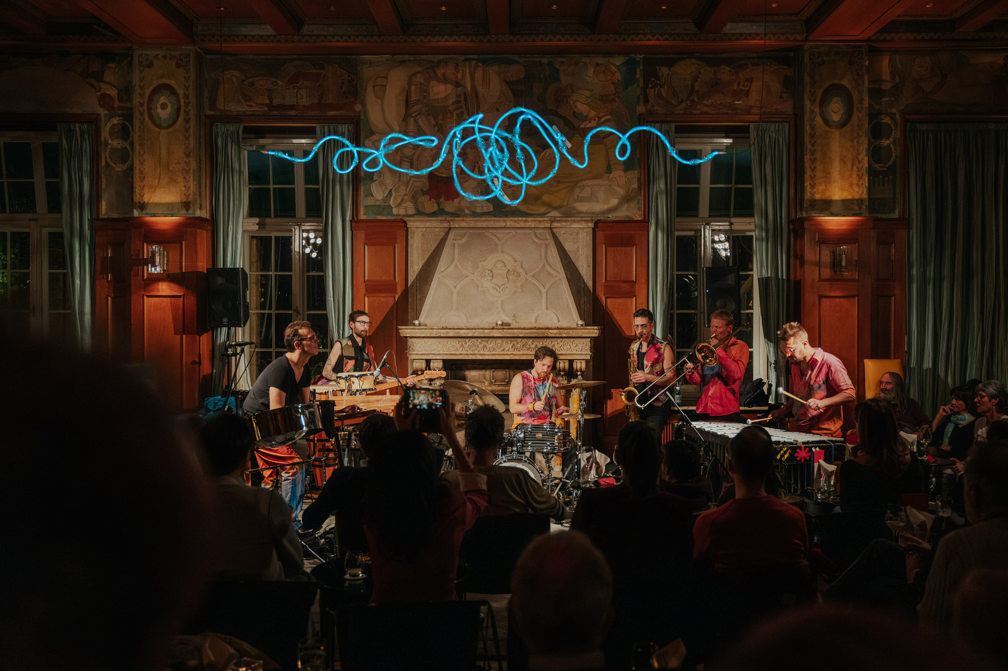 Musicians performing on stage at Laurin Bar, with colorful lights and an audience in a historic setting.