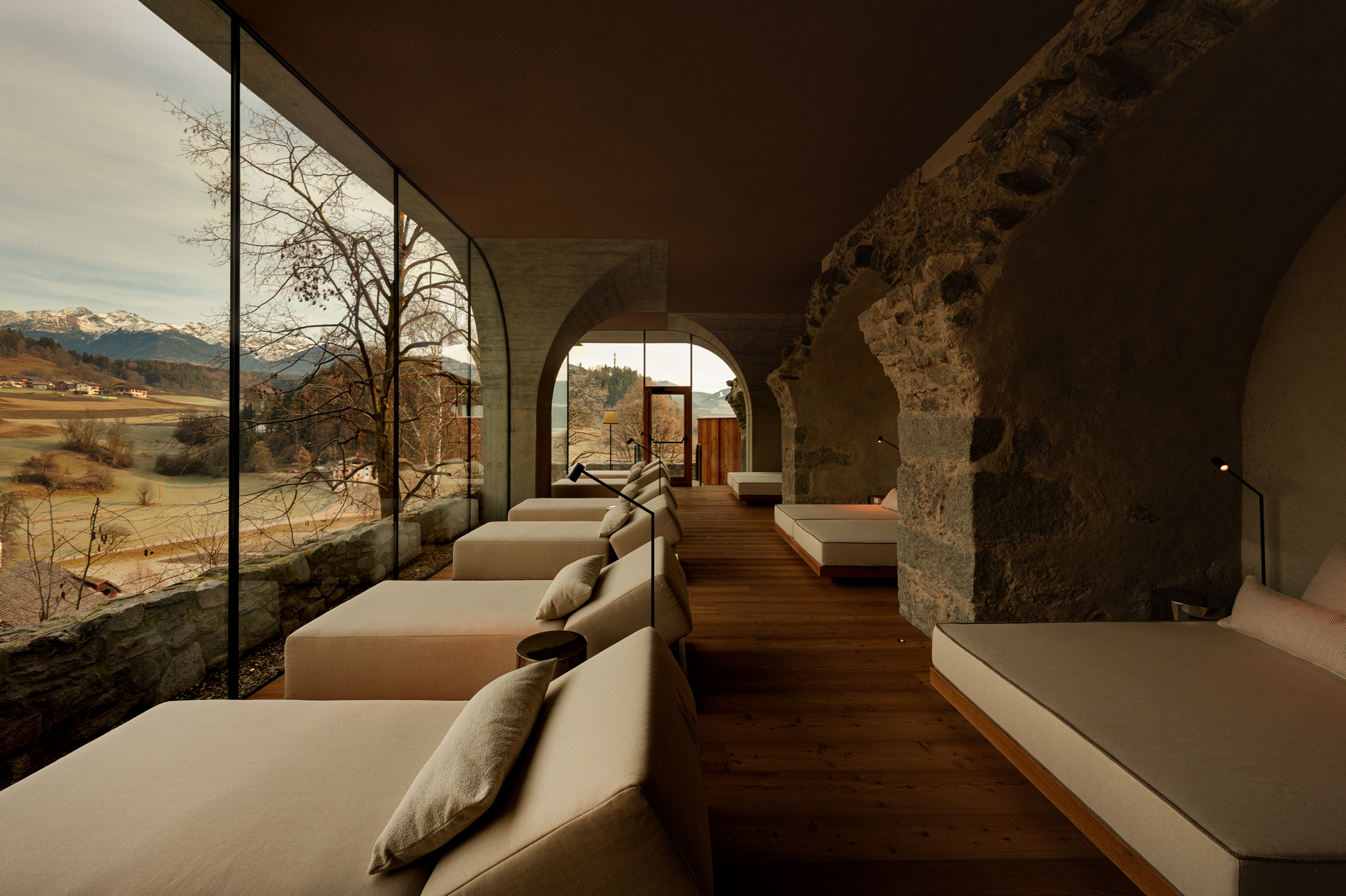 Modern interior of Castel Badia featuring minimalist beds and large windows with a scenic mountain view.