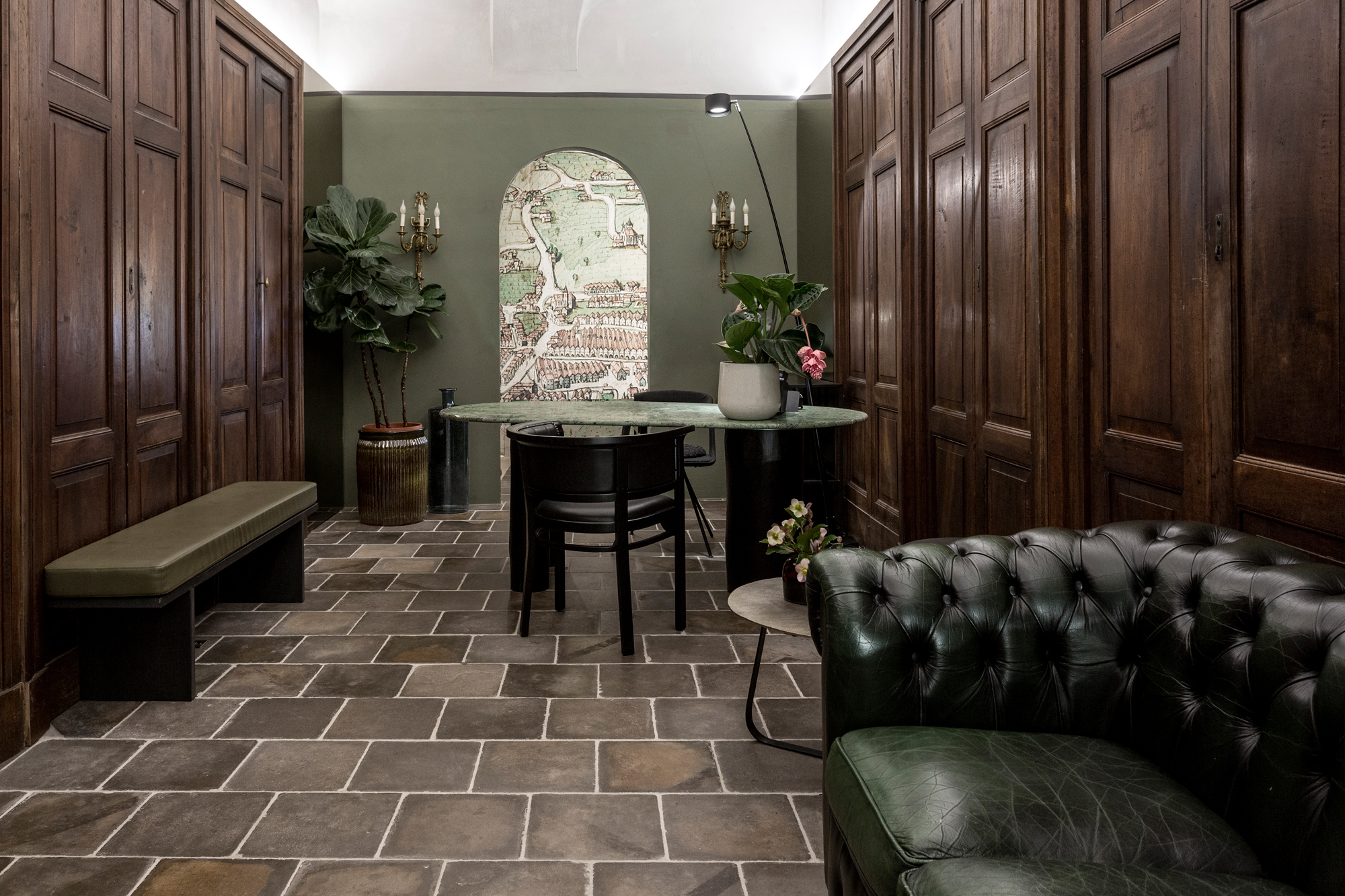 Reception area of Goldenstern Townhouse featuring wooden paneling, a green couch, a table, and a decorative wall map.