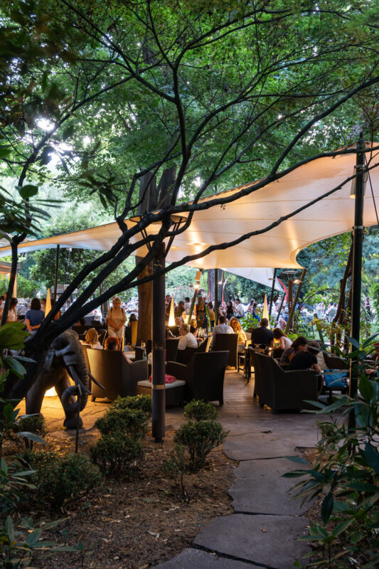 Outdoor seating area at Parkhotel Laurin, featuring a canopy, lush greenery, and guests enjoying the ambiance.