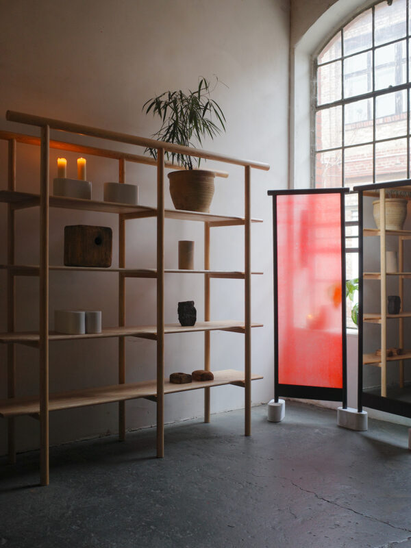 Fusuma shelf by Marco Zebrowski, featuring wooden shelves, decorative items, and a red screen beside a large window.