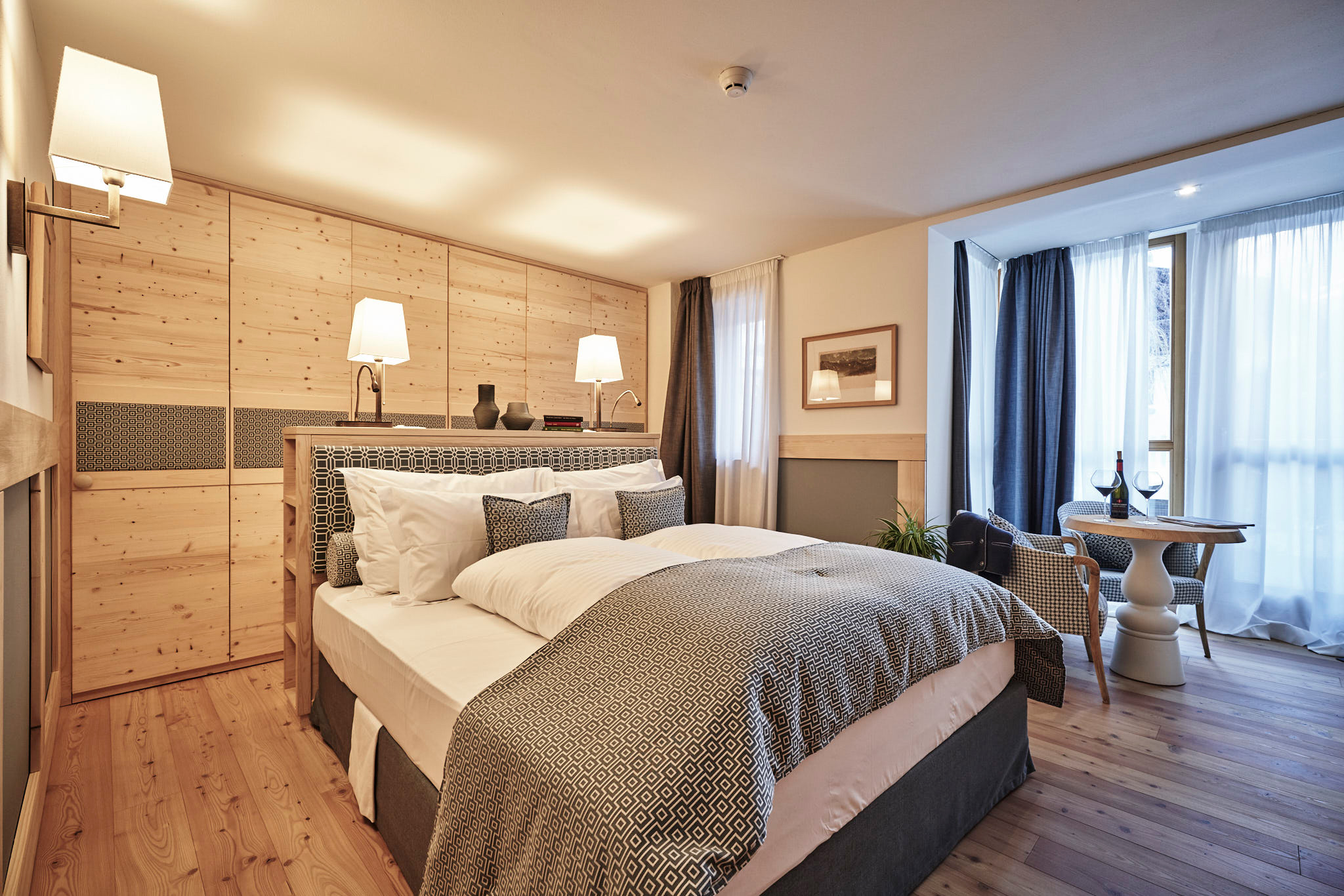 Cozy Grand Deluxe Room with wooden accents, a double bed, and a seating area by the window at Goldene Rose.