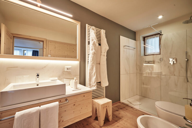 Modern bathroom featuring a wooden vanity, large mirror, shower area, and neutral tones, part of the Grand Deluxe Room.