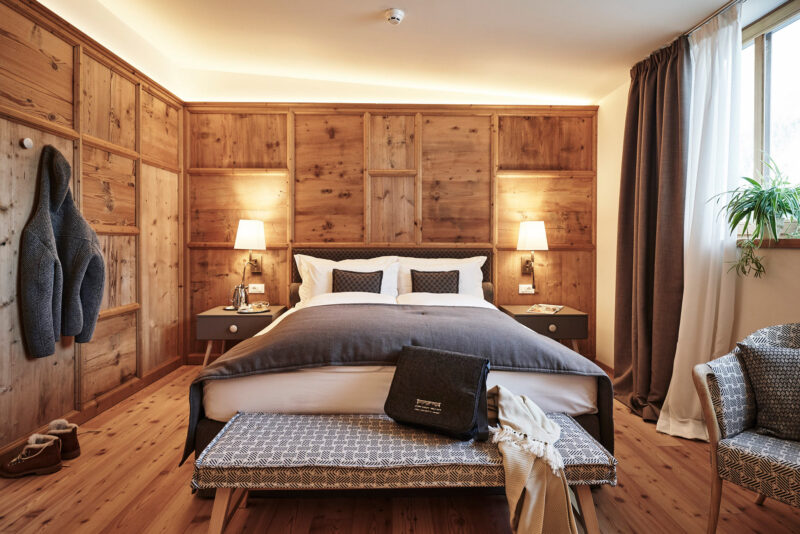 Cozy superior room with wooden paneling, a double bed, bedside tables, and a seating area, featuring warm lighting.