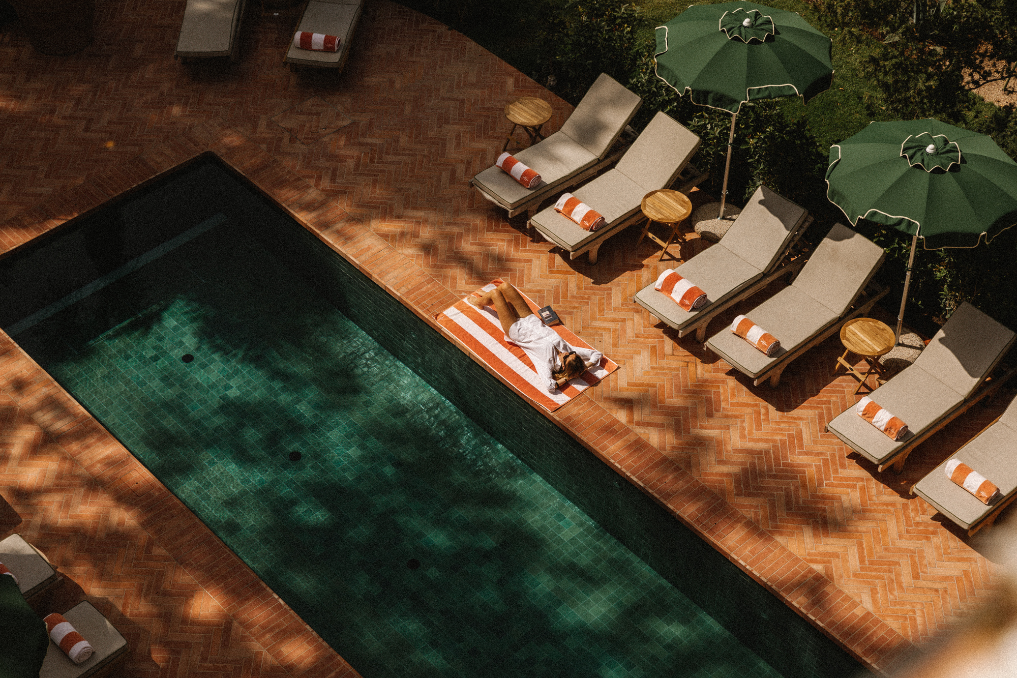 Aerial view of a pool area at Parkhotel Mondschein, featuring lounge chairs and a person relaxing on a float.
