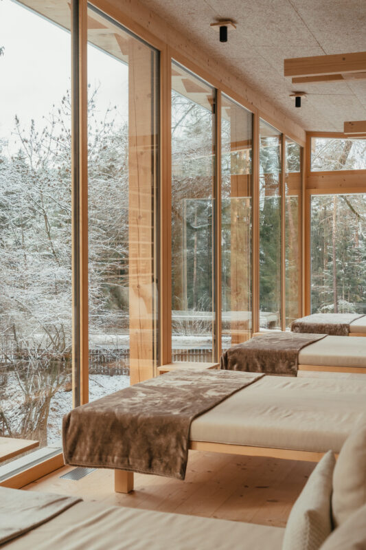 Relaxation area with wooden loungers and large windows overlooking a snowy landscape in the Dolomites.