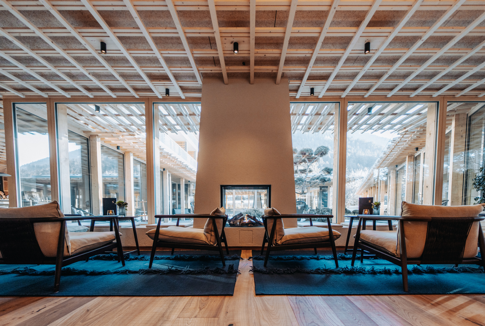 Stylish seating area with two chairs facing a fireplace, large windows showing a mountain view in the background.