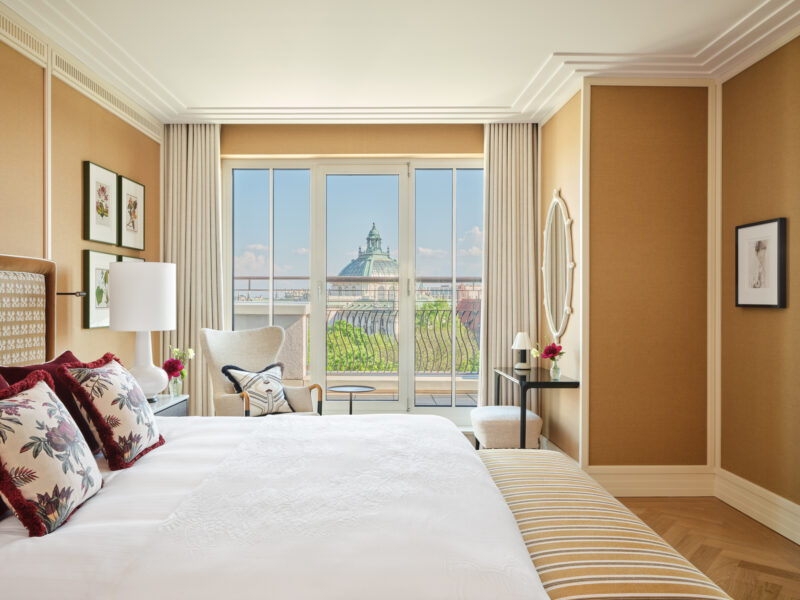 Elegant bedroom in the Monforte Suite at The Charles Hotel, featuring a view of a dome through large windows.
