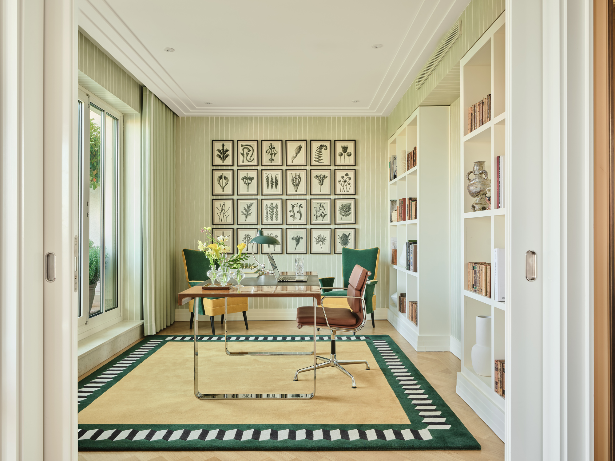 Elegant study in the Monforte Suite at The Charles Hotel, featuring a desk, bookshelves, and botanical artwork.