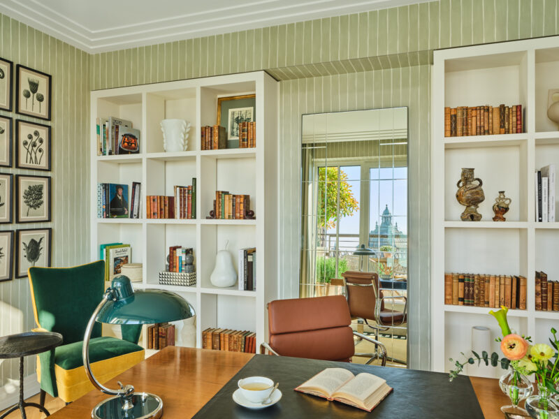 Study area in the Monforte suite at The Charles Hotel, featuring bookshelves, a desk with a lamp, and a view of the city.
