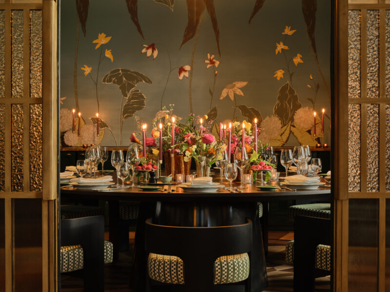 Elegant private dining room at The Charles Hotel, featuring a round table set with flowers, candles, and fine tableware.