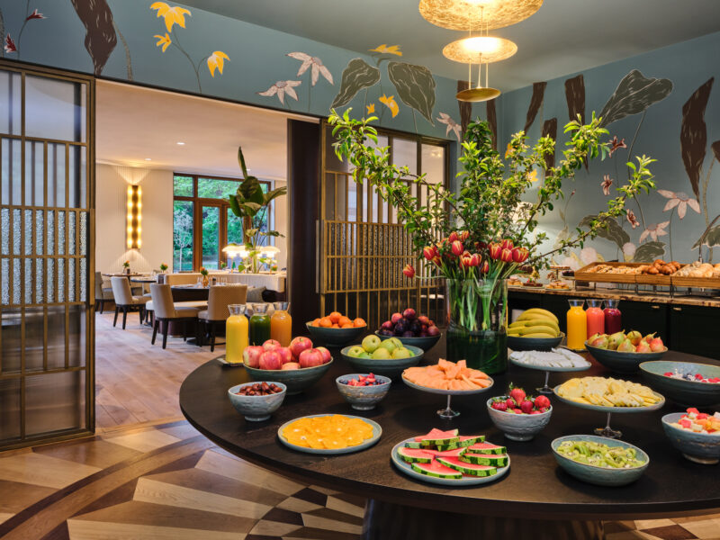 Colorful breakfast spread with fruits, juices, and pastries, set in a stylish dining area at The Charles Hotel.