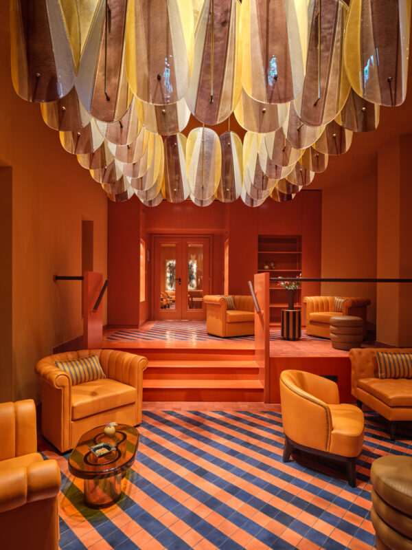 Vibrant interior of The Florentin Cigar Bar featuring orange seating, a patterned floor, and a unique ceiling design.
