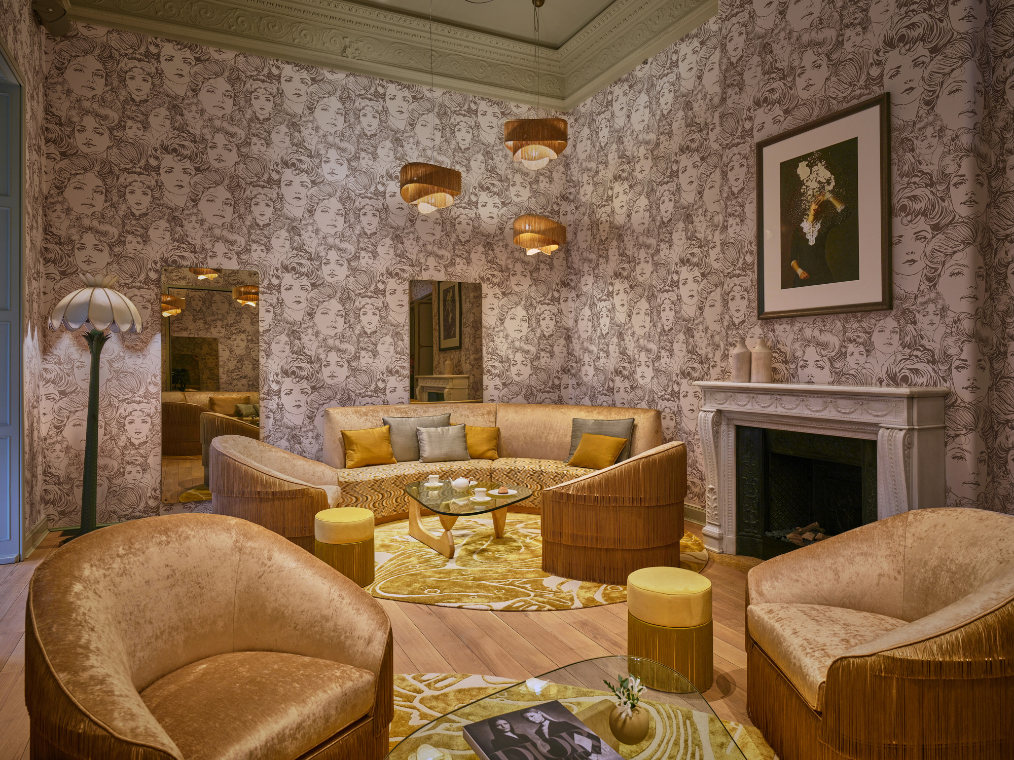Stylish lounge with patterned wallpaper, circular seating, and modern lighting, featuring a fireplace and decorative accents.