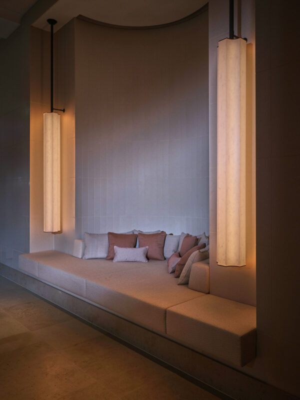 Cozy spa lounge area with soft cushions and ambient lighting from tall, modern lamps.