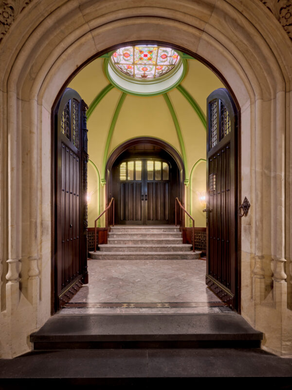 Elegant entrance of a villa featuring arched doorways, a stained glass dome, and a staircase leading to a wooden door.