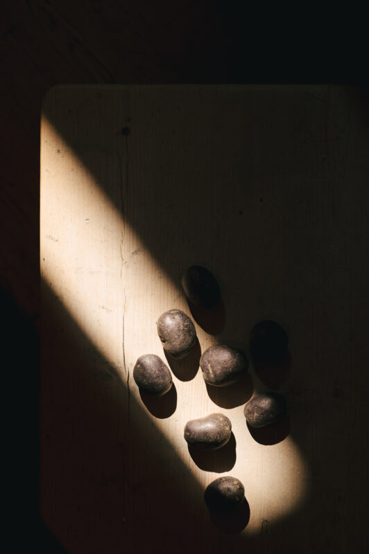 Dark stones arranged on a wooden surface, illuminated by a beam of light.