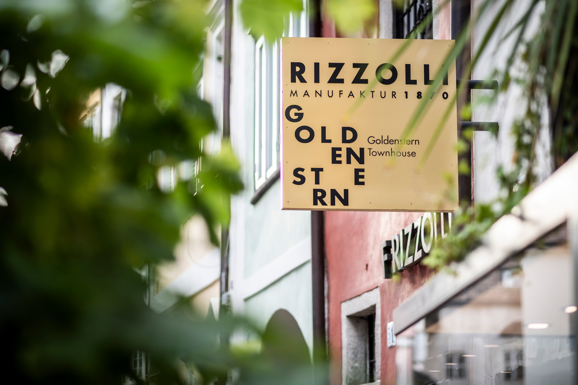Sign for "Goldenstern Townhouse" with green foliage in the foreground, featuring the Rizzoli logo.