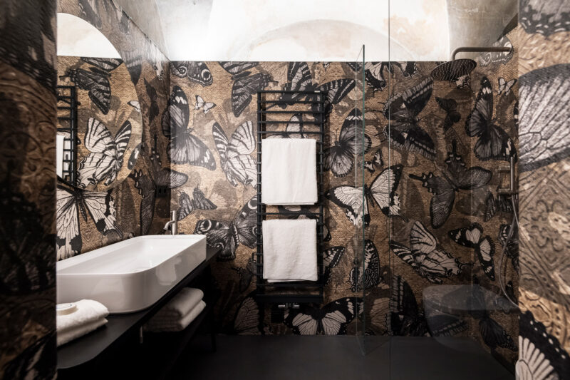 Luxurious bathroom featuring butterfly-patterned wallpaper, a modern sink, and neatly arranged towels.