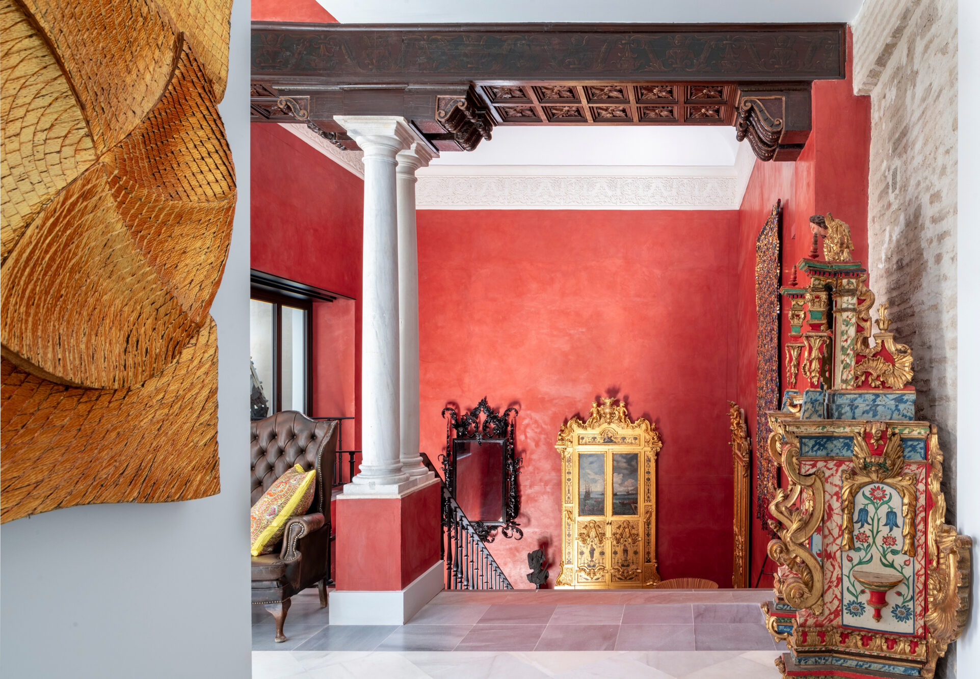 Interior of Hotel Casa Limonero featuring a red wall, ornate decor, a column, and a decorative gold mirror.