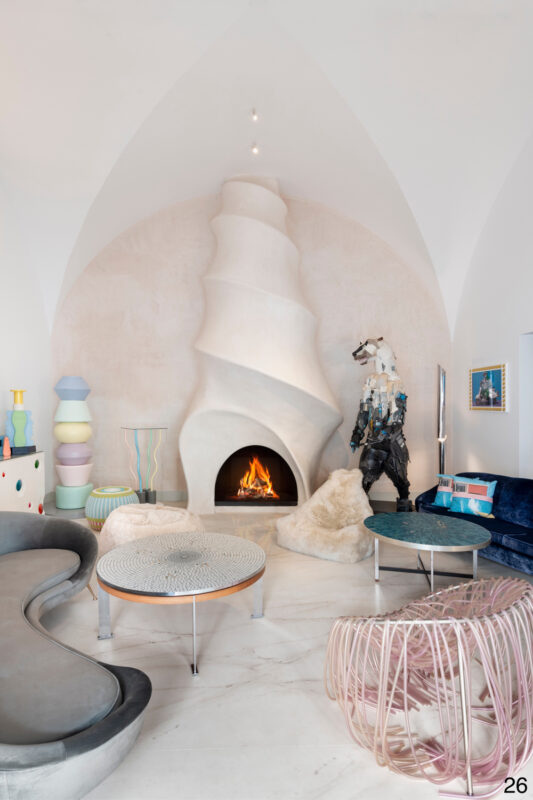 Modern hotel lounge featuring a sculptural fireplace, colorful furniture, and artistic decor.