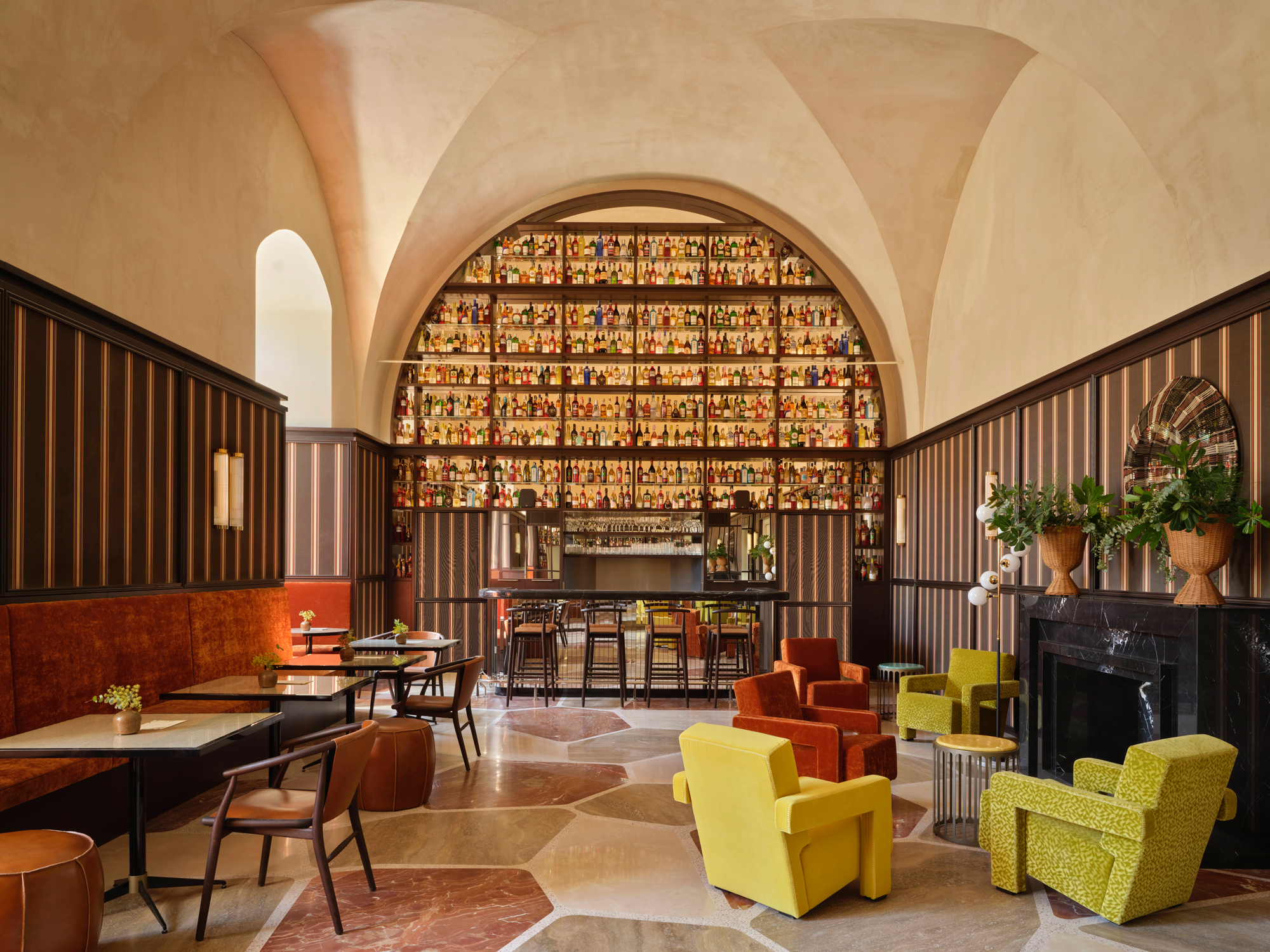 Stylish bar area in Villa Ostuni with colorful chairs, a patterned floor, and shelves filled with bottles.