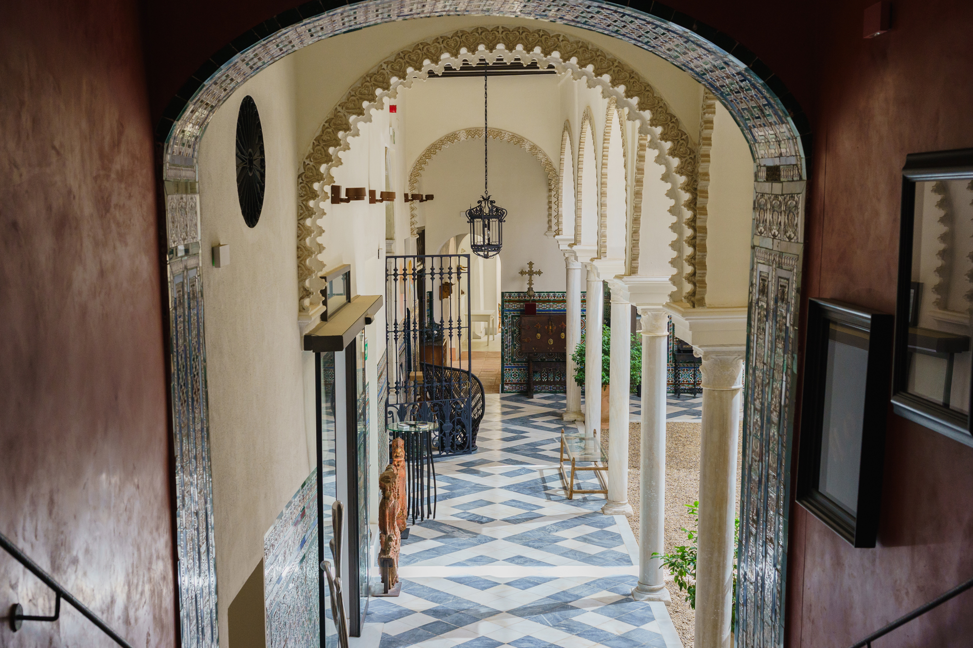 View of a main staircase in Casa del Limonero, featuring intricate arches and patterned floor tiles.