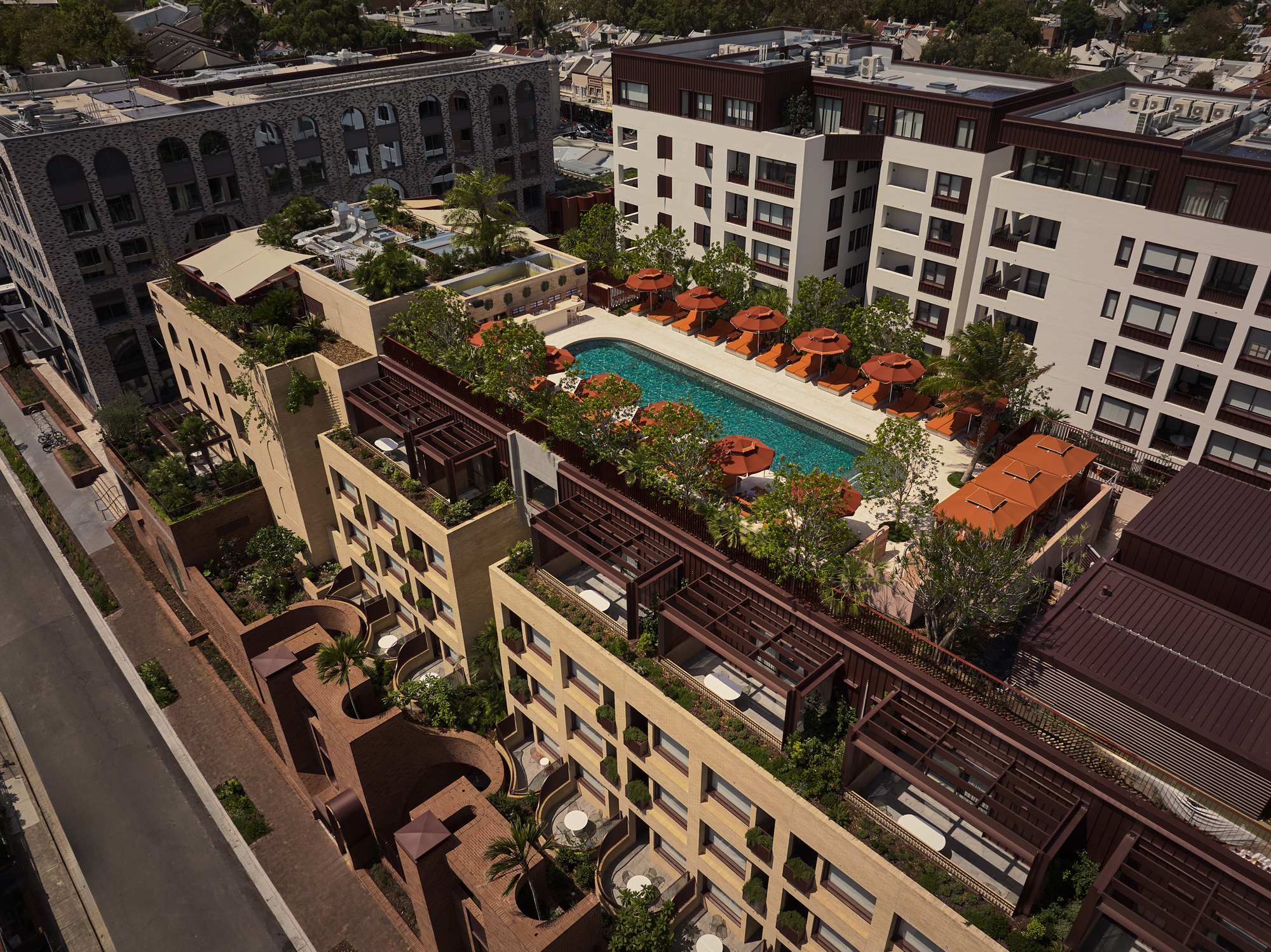 Aerial view of The EVE Hotel Sydney, showcasing the pool area with orange loungers and landscaped terraces.