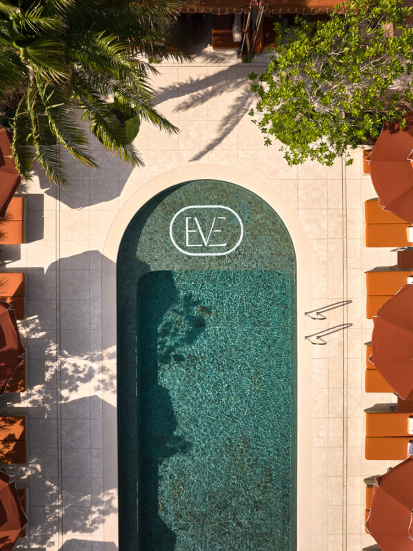 Aerial view of a pool at The EVE Hotel Sydney, featuring lounge chairs and the logo "EVE" on the pool floor.