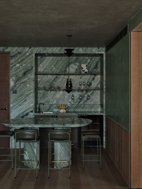Modern kitchen featuring green marble walls, a round marble table, and sleek bar stools in The EVE Hotel Sydney.