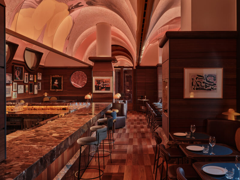 Elegant bar interior at The EVE Hotel Sydney, featuring a marble counter, stylish seating, and artistic decor under soft l...