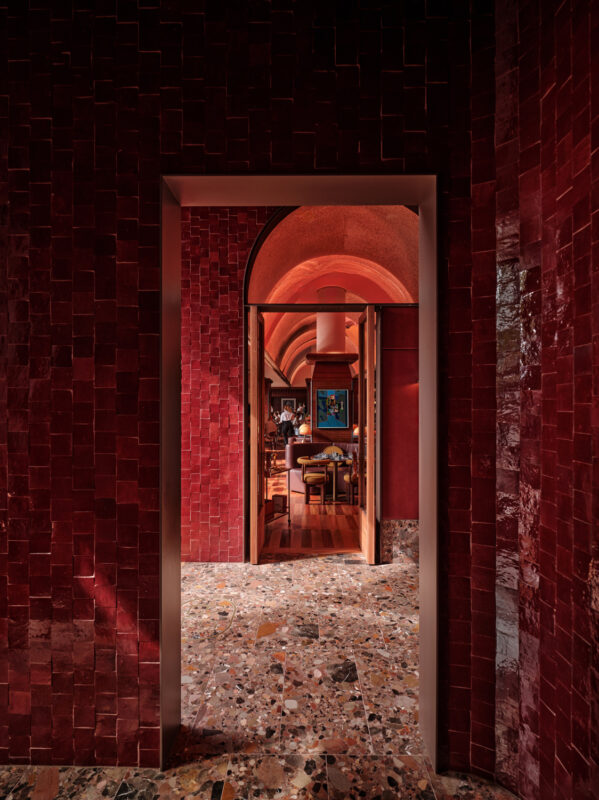 View through a red-tiled archway into the EVE Bar, showcasing vibrant decor and wooden flooring.