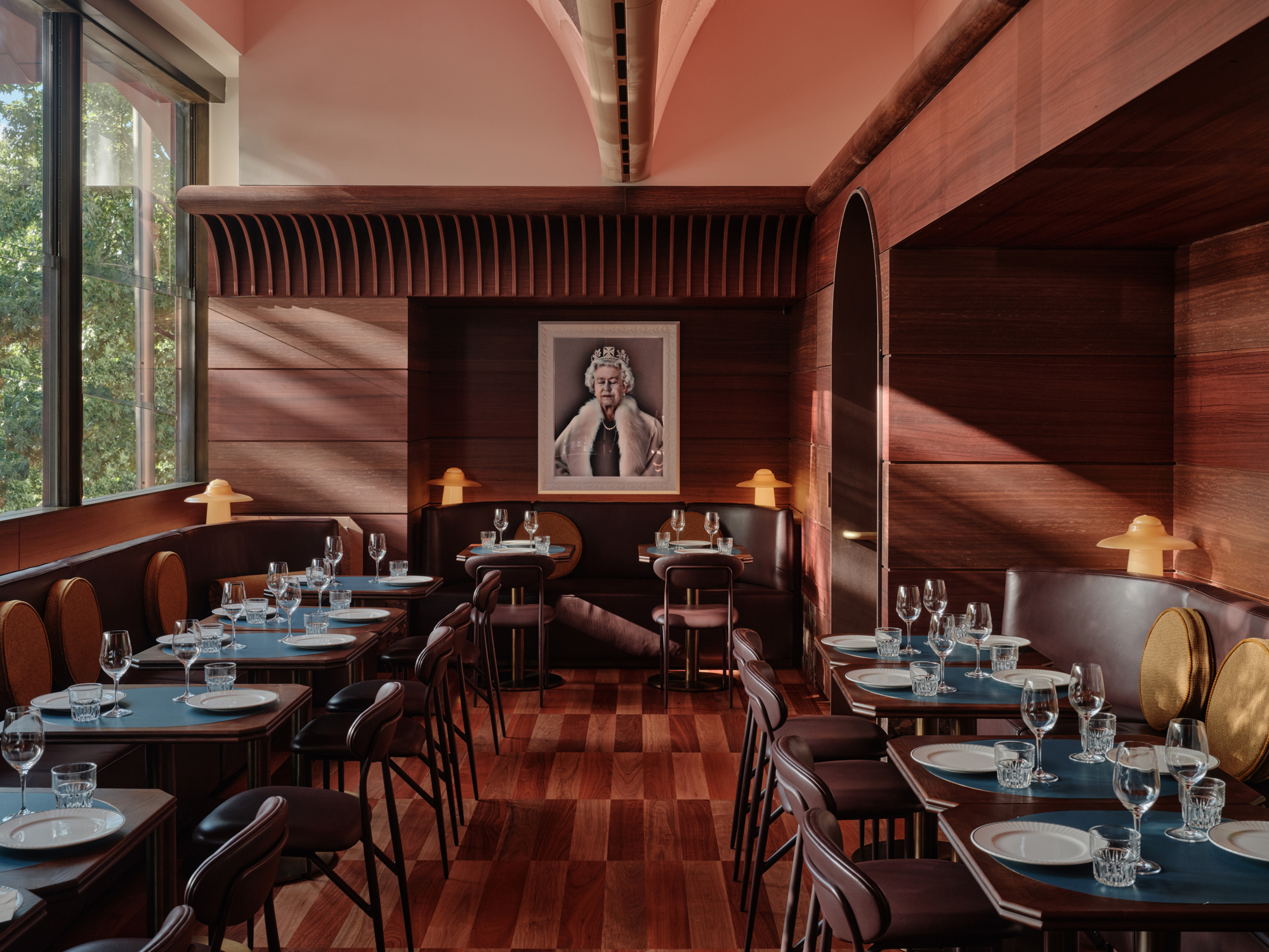 Elegant dining area of The EVE Hotel Sydney featuring wooden decor, tables set with glassware, and a portrait on the wall.