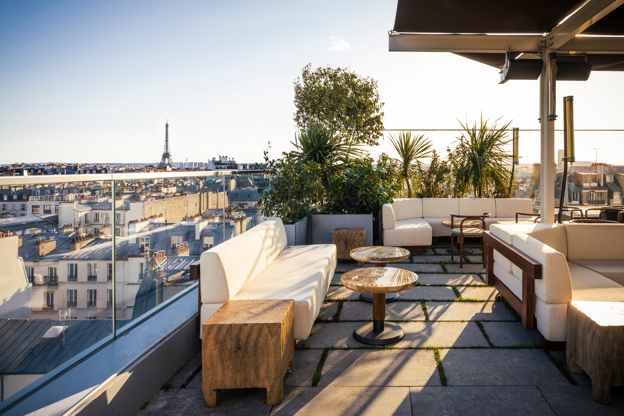 Rooftop terrace of La Fondation hotel with seating, plants, and a view of Paris rooftops and the Eiffel Tower.
