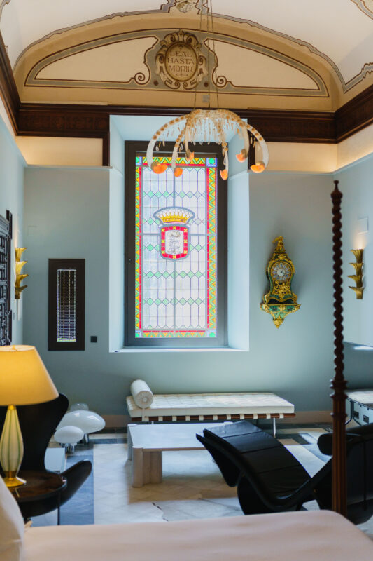 Elegant room featuring a stained glass window, ornate chandelier, and stylish furniture, part of Casa del Limonero.
