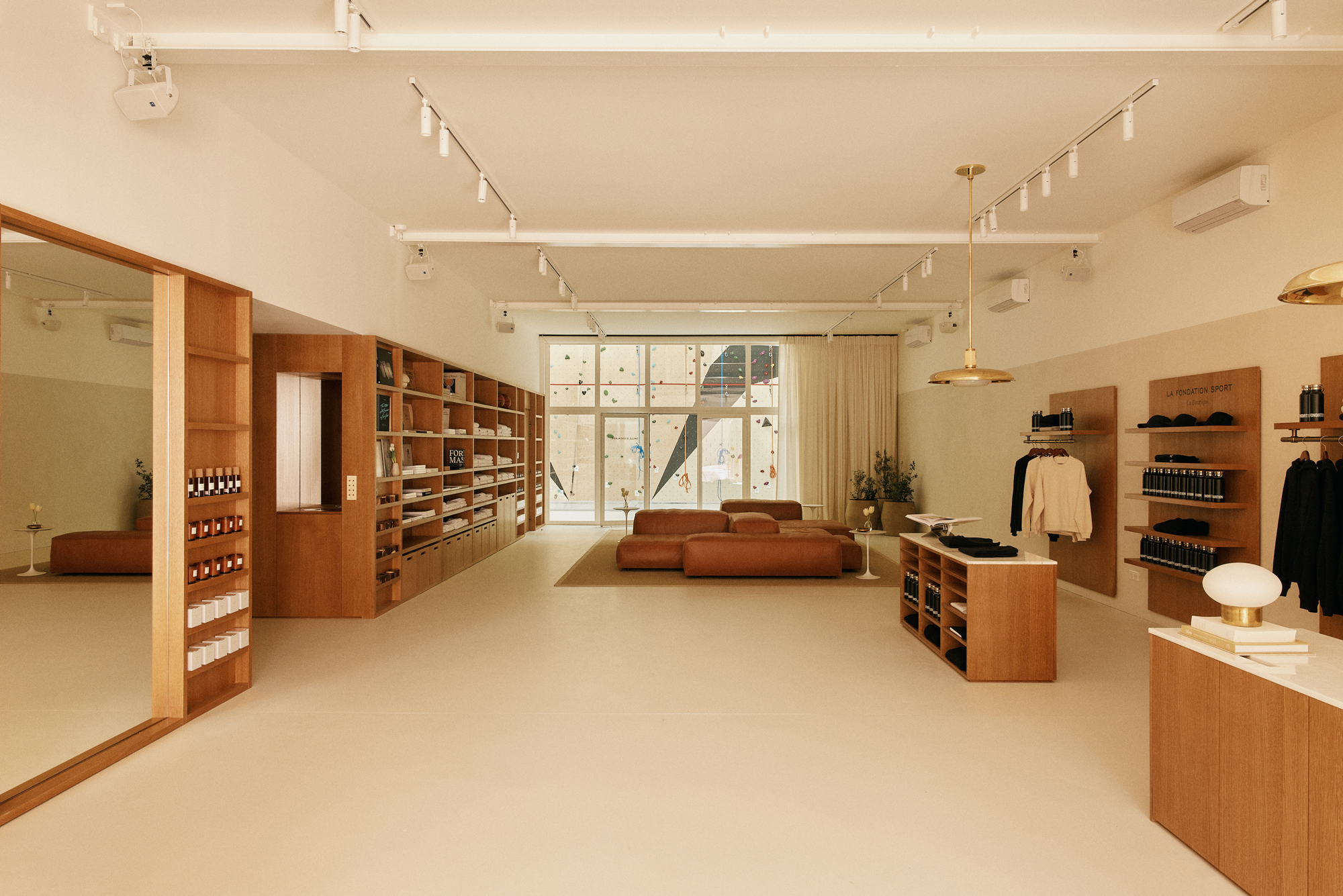 Minimalist interior of La Fondation Paris featuring a lounge area, wooden shelves, and natural light from large windows.