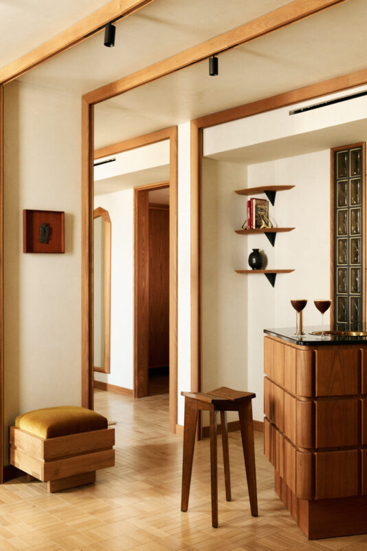Warm-toned interior of La Fondation Hotel featuring wooden furniture, a bar area, and decorative shelves.