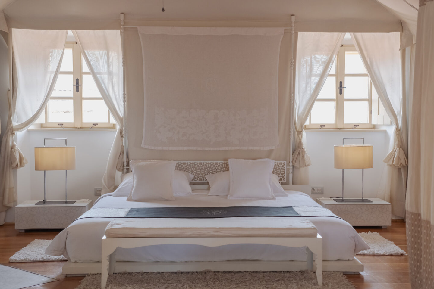 Elegant bedroom in Lešić Dimitri Palace featuring a white bed, decorative pillows, soft lighting, and sheer curtains.