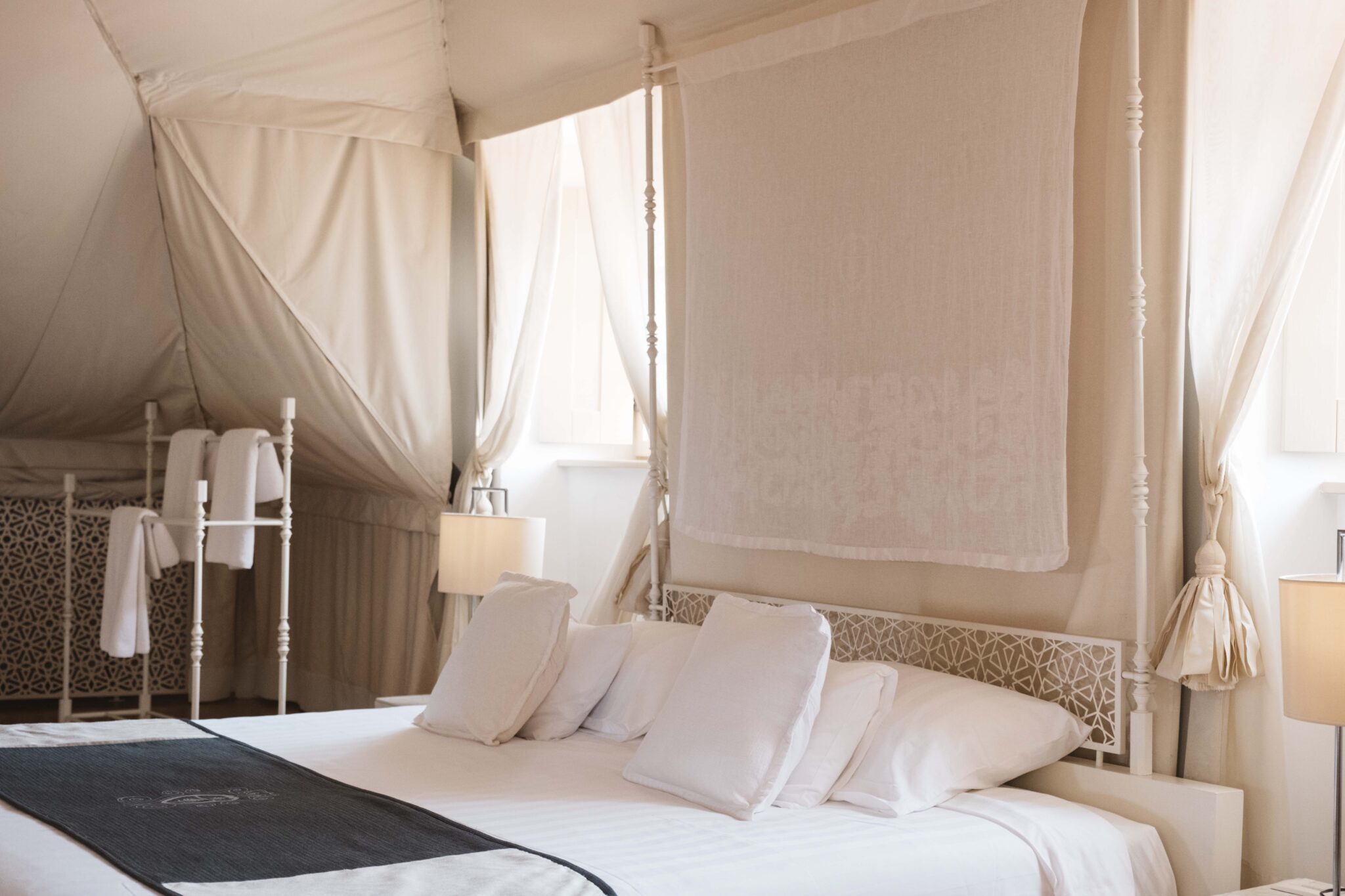 Luxurious bedroom in LD Arabia residence with a white bed, decorative headboard, and soft lighting.