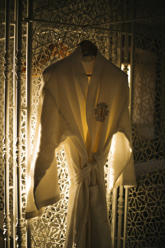 White bathrobe hanging on a decorative screen, illuminated from behind, showcasing intricate patterns.