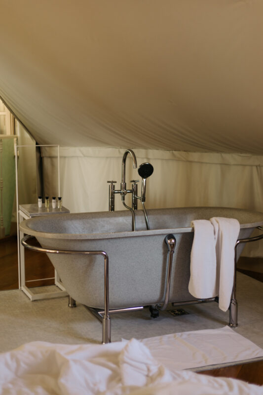 Stylish freestanding bathtub with a showerhead, white towels, and toiletries in a tent-like room at Lešić Dimitri Palace.