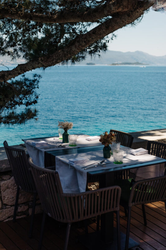 Table set for dining with flowers and glasses, overlooking a tranquil sea at Lešić Dimitri Palace.