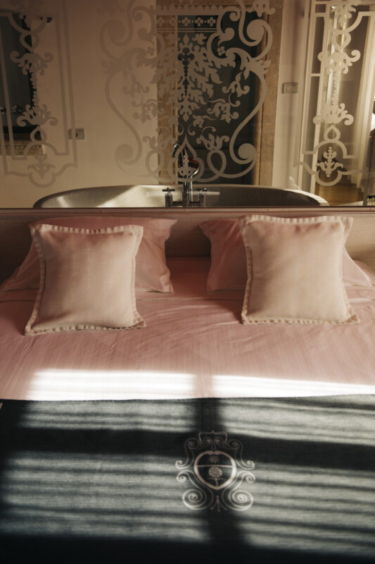 Elegant hotel room at Lešić Dimitri Palace featuring a bed with pink pillows and a stylish bathtub in the background.