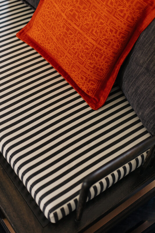 Striped black and white cushion on a bench with a vibrant orange decorative pillow at Lešić Dimitri Palace.