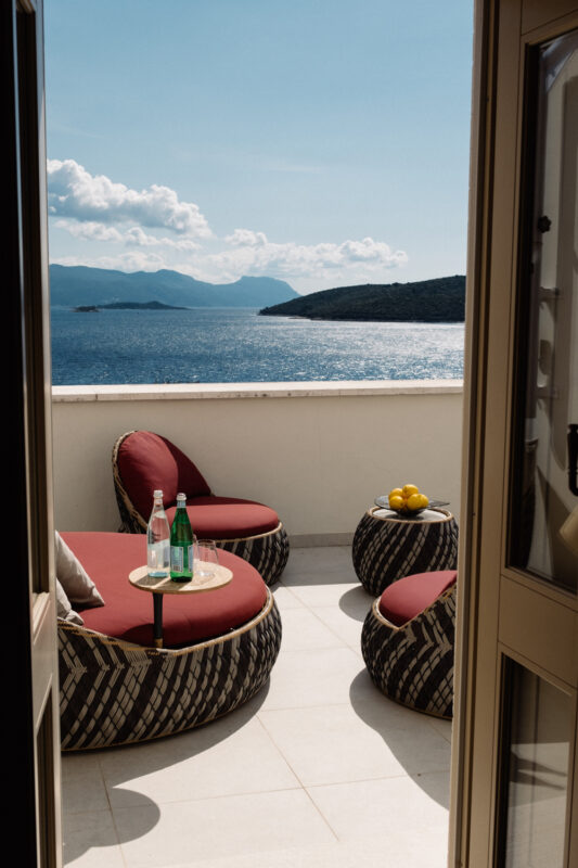 Balcony view at Lešić Dimitri Palace with two round chairs, a table, and a scenic sea backdrop.