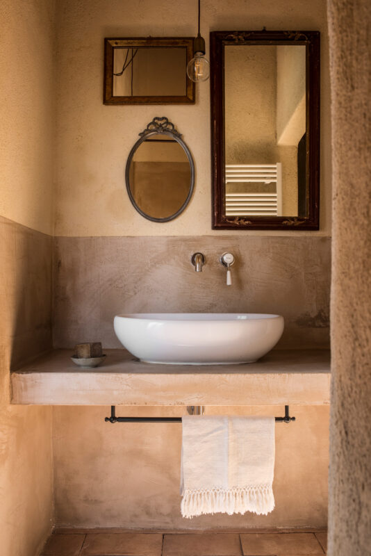 Minimalist bathroom featuring a white basin on a stone countertop, framed mirrors, and a towel hanging below.