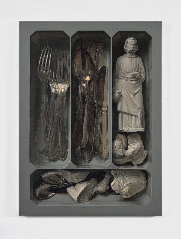 Cutlery and figurines arranged in a gray tray, showcasing forks, spoons, and small sculptures.