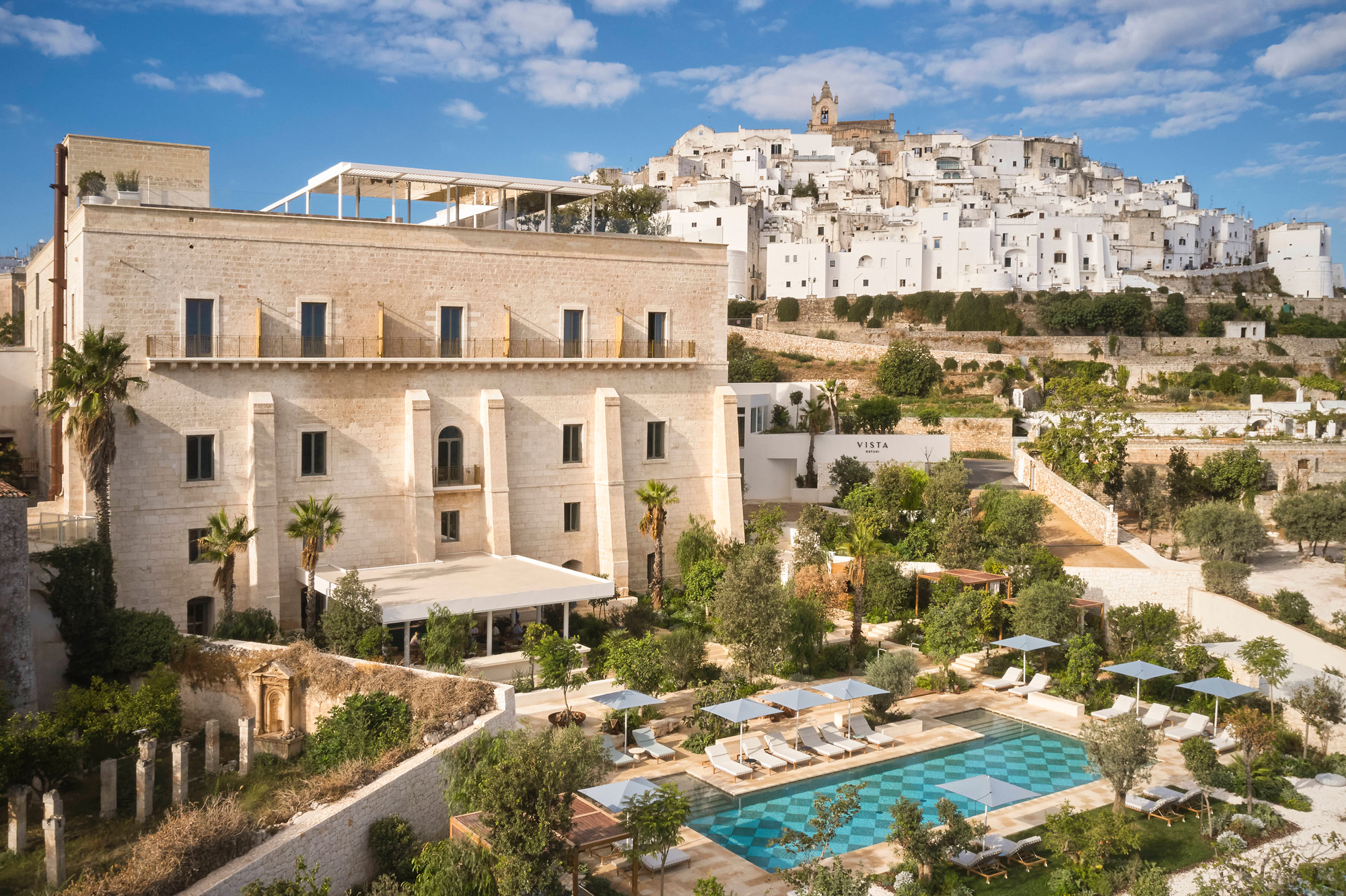 Villa Ostuni with a pool and gardens, overlooking the white buildings of Ostuni under a blue sky.