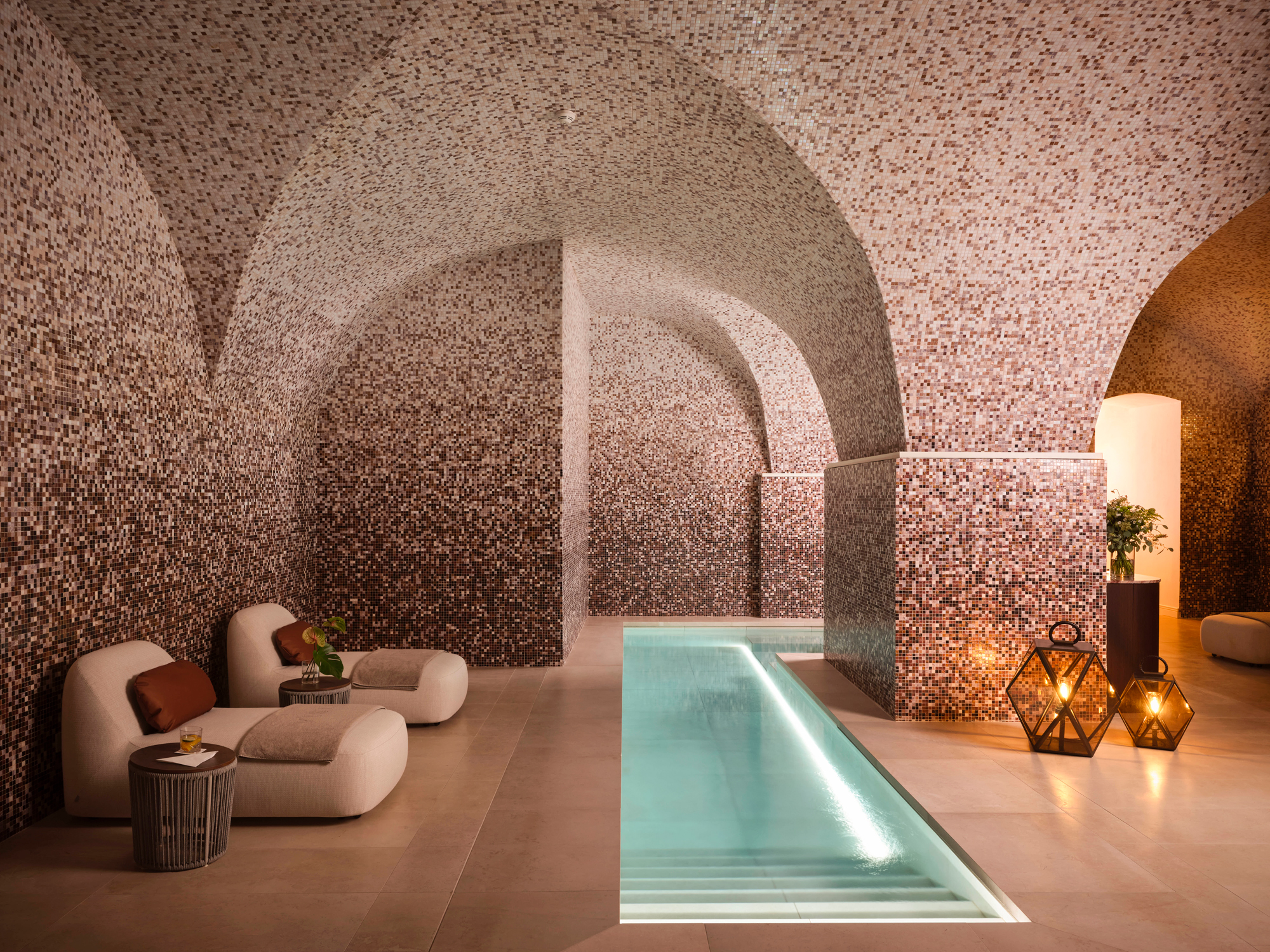 Spa interior featuring a serene internal pool, mosaic walls, and cozy seating with ambient lighting.