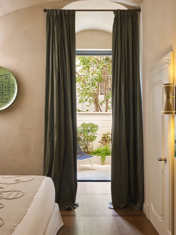 View of a deluxe private garden through a doorway, with green curtains and a modern chair visible.